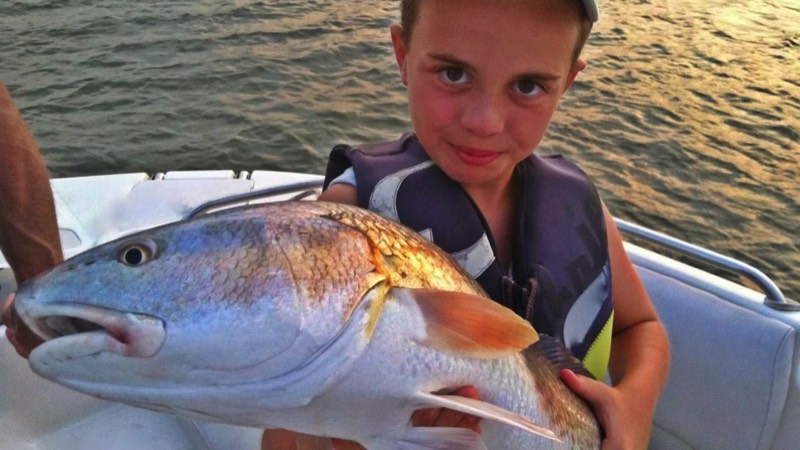 child angler holds up red fish caught on Hilton Head fishing charter